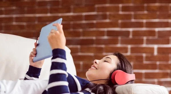 Mujer asiática tumbada en el sofá escuchando música —  Fotos de Stock