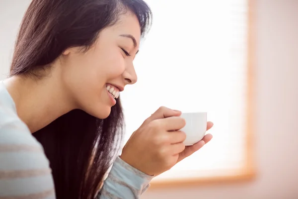 Asian woman relaxing on couch with coffee — Stock Photo, Image