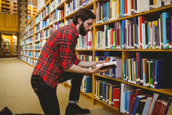 Студент вибирає книгу з полиці в бібліотеці — стокове фото