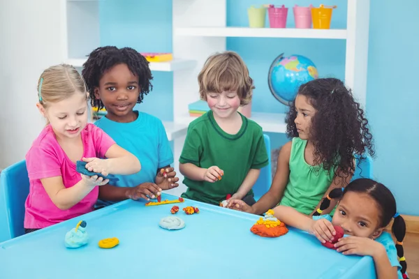 Smiling kids playing with modelling clay — Stock Photo, Image