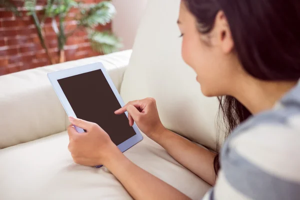 Sonriendo mujer asiática en sofá usando tableta —  Fotos de Stock