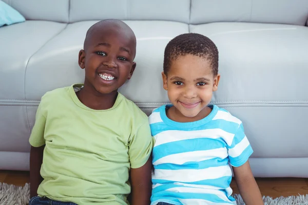 Niños sonrientes sentados junto al sofá — Foto de Stock