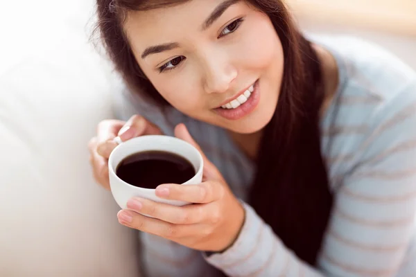 Азиатка отдыхает на диване с кофе — стоковое фото
