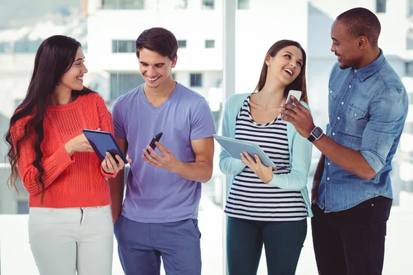 Equipe criativa olhando para telefones e tablets — Fotografia de Stock