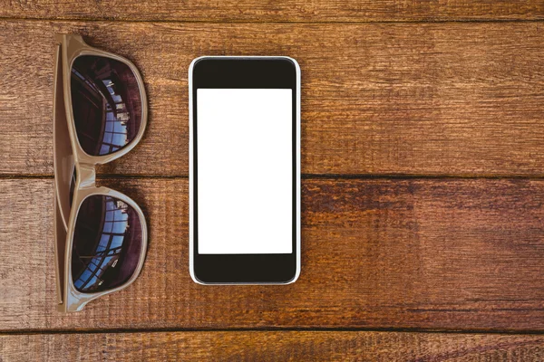 Glasses and smartphone on wood desk — Stock Photo, Image