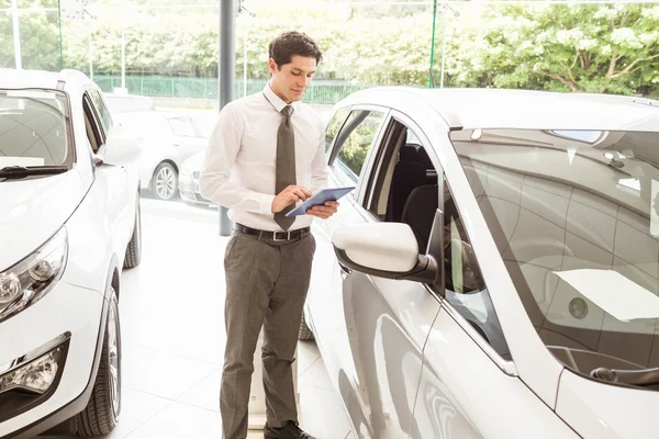 Lächelnder Verkäufer mit Tablet in der Nähe eines Autos — Stockfoto