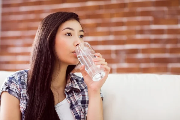 Mujer asiática en el sofá agua potable — Foto de Stock