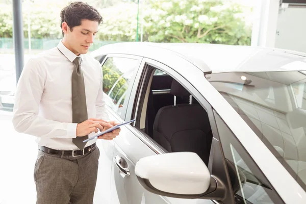 Leende försäljare använda tablet nära en bil — Stockfoto