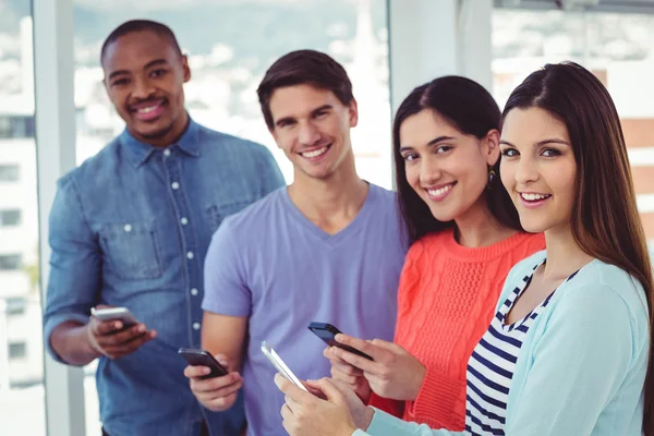 Jeune équipe créative regardant les téléphones — Photo