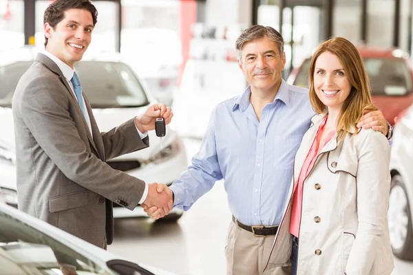 Vendedor dando chave de carro para um casal — Fotografia de Stock