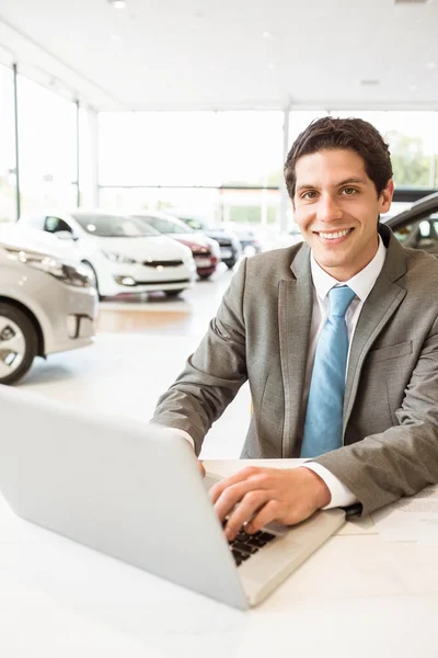 Smiling salesman writing on his laptop — Stock Photo, Image