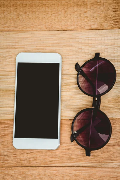 Occhiali e smartphone sulla scrivania in legno — Foto Stock
