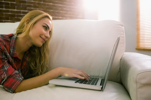 Hezká blondýnka relaxační na gauči, přes notebook — Stock fotografie