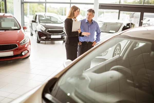 Geschäftsfrau und Kunde schauen sich ein Auto an — Stockfoto