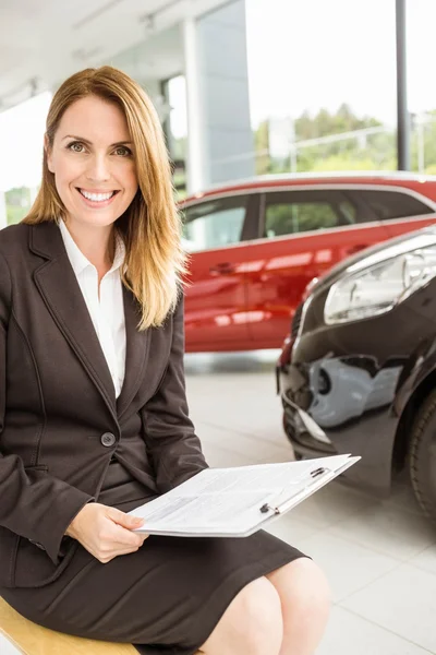 Vendedora sorridente sentada perto de carros — Fotografia de Stock