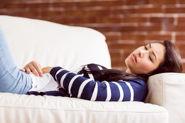 Asiatin liegt mit Krämpfen auf der Couch — Stockfoto