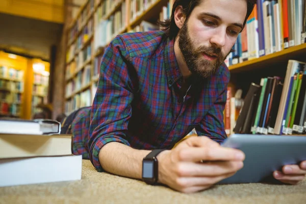 Студент, який навчається на підлозі в бібліотеці, носить розумний годинник — стокове фото
