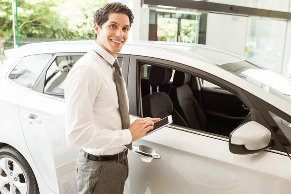 Vendedor sonriente usando tableta cerca de un coche — Foto de Stock