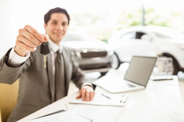 Venditore sorridente che tiene una chiave dell'automobile del cliente — Foto Stock