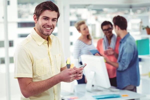 Empresario creativo usando smartphone frente a colegas — Foto de Stock