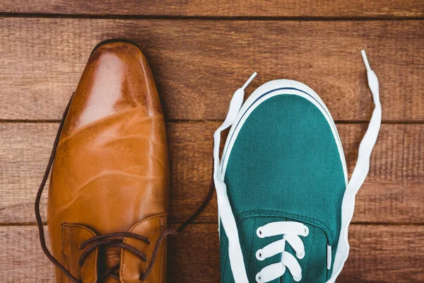 Twee verschillende schoenen op houten plank — Stockfoto