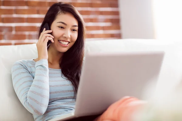 Asian woman on the phone using laptop — Stock Photo, Image