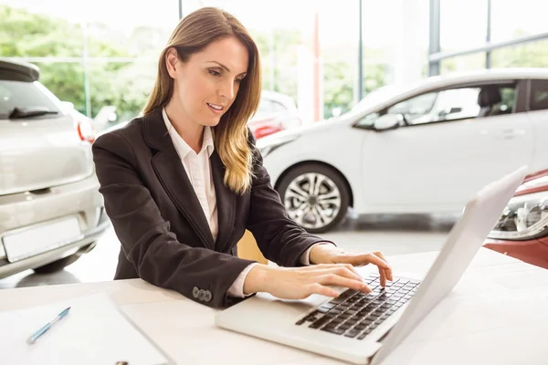 Lächelnde Verkäuferin tippt auf ihrem Laptop — Stockfoto