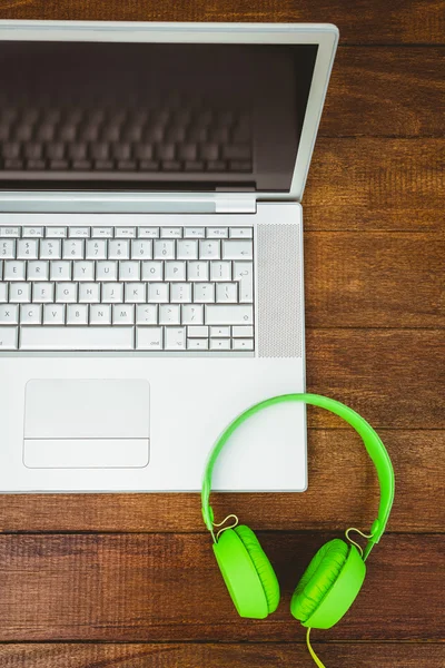 Grijze laptop met groene hoofdtelefoon — Stockfoto