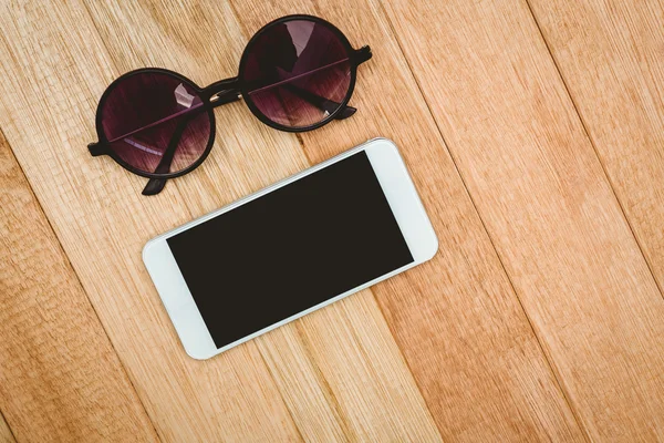 Óculos e um smartphone na mesa de madeira — Fotografia de Stock