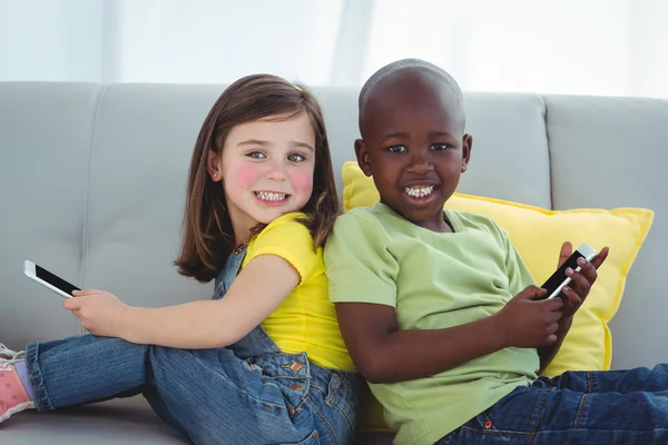 Leende flicka och pojke använda mobiltelefoner — Stockfoto