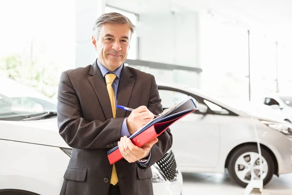 Lächelnder Verkäufer schreibt an Arbeitsbüchern — Stockfoto