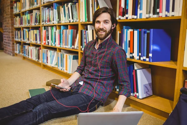 Student pomocí telefonu v knihovně na podlaze — Stock fotografie