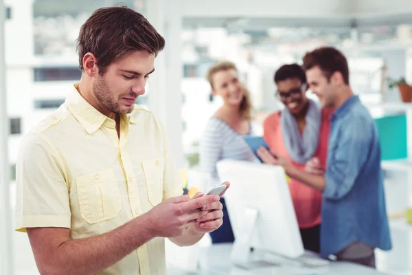 Творческий бизнесмен использует смартфон перед коллегами — стоковое фото