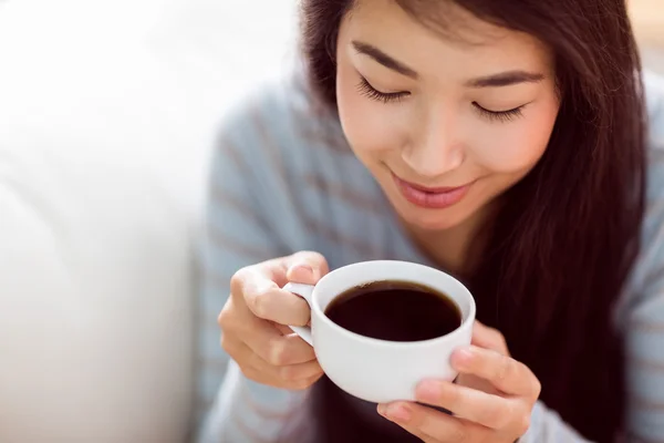 Азиатка отдыхает на диване с кофе — стоковое фото