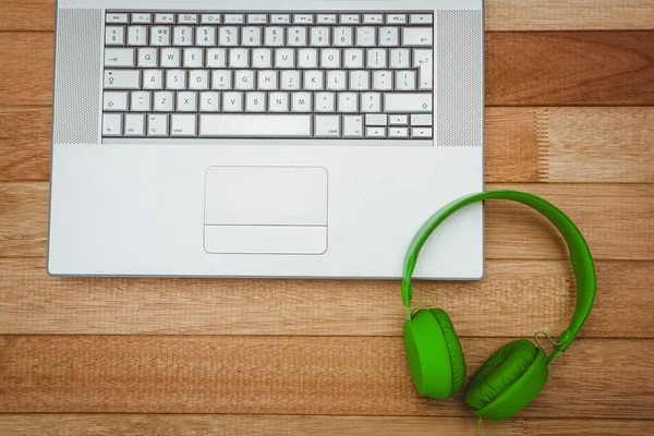 Γκρίζο φορητό υπολογιστή με ένα πράσινο ακουστικών — Φωτογραφία Αρχείου