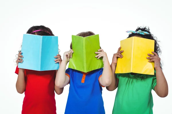 Drei Kinder mit Büchern vor dem Gesicht — Stockfoto