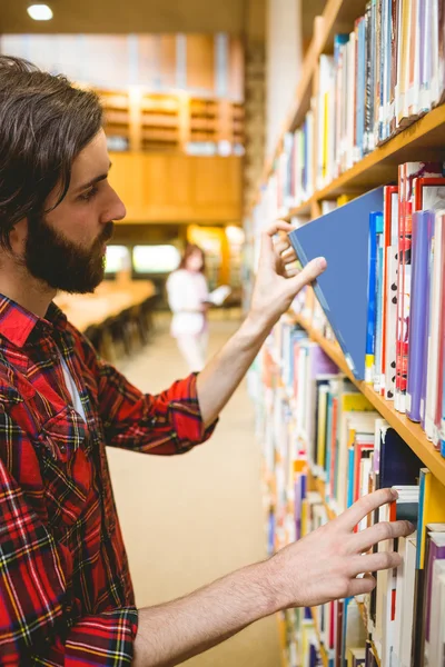 Étudiant hippie qui choisit un livre à la bibliothèque — Photo