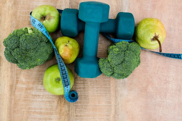 Dumbbells and fruits on wooden table — Stock Photo, Image