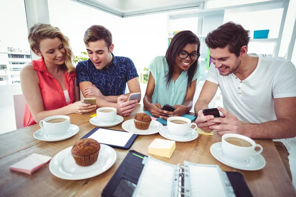 Equipo creativo trabajando juntos en teléfonos inteligentes —  Fotos de Stock