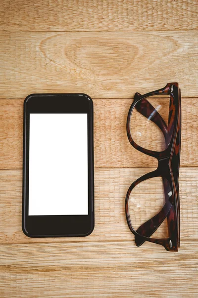 Gafas y un smartphone en escritorio de madera —  Fotos de Stock