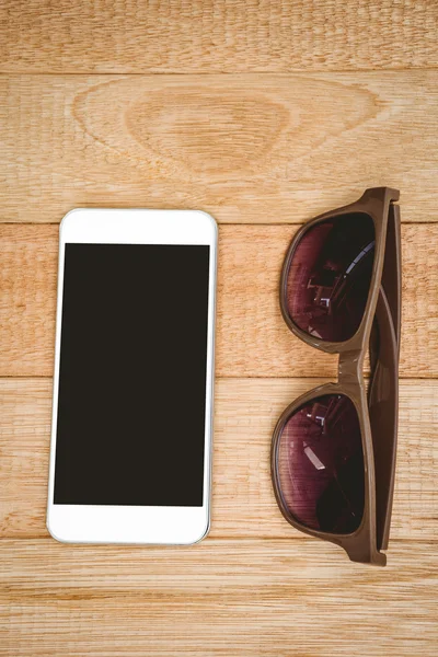 Óculos e smartphone na mesa de madeira — Fotografia de Stock