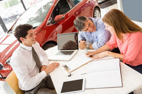 Clientes assinando documentos no showroom do carro — Fotografia de Stock