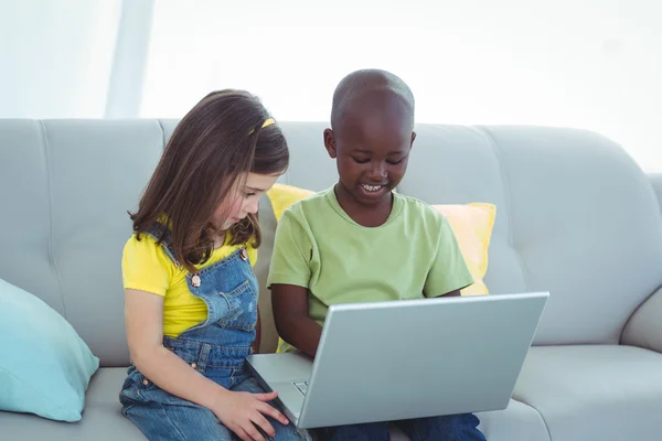 Sonriente niña y niño usando un ordenador portátil — Foto de Stock