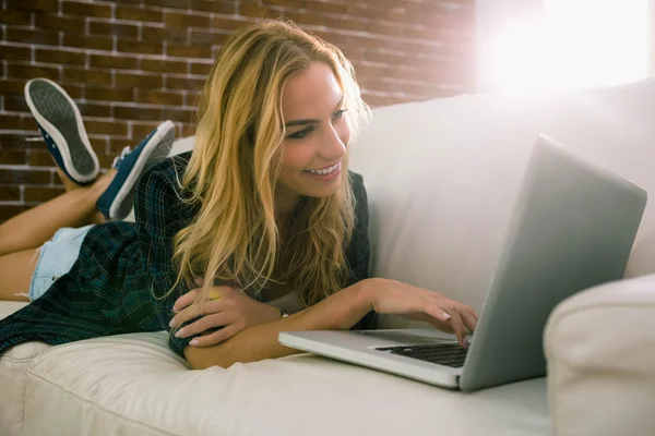 Vackra blonda avkopplande på soffan med laptop — Stockfoto