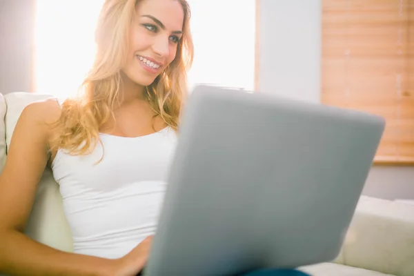 Vackra blonda med laptop på soffan — Stockfoto