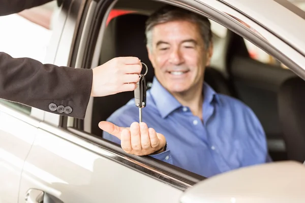 Verkäufer übergibt Schlüssel an lächelnden Geschäftsmann — Stockfoto