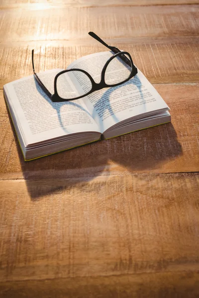 Book and glasses on wood desk — Stock Photo, Image