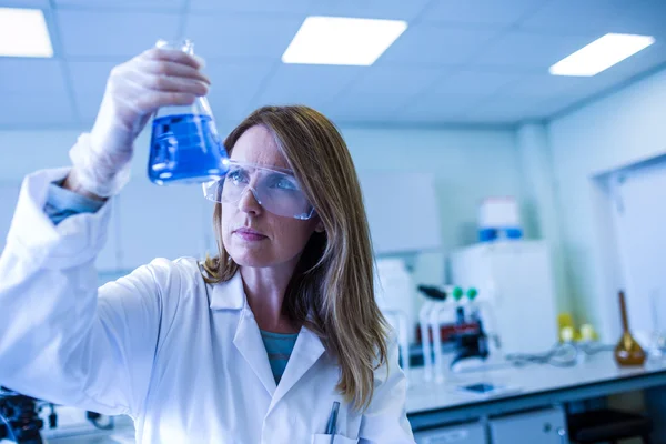 Scientist holding up beaker of chemical — Stock Photo, Image