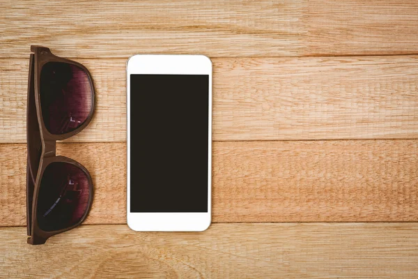 Очки и смартфон на деревянном столе — стоковое фото