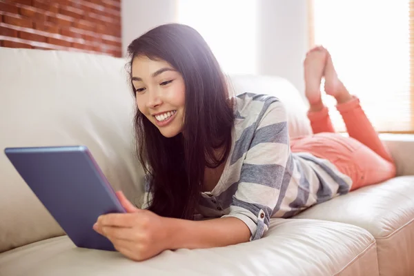 Sorrindo mulher asiática no sofá usando tablet — Fotografia de Stock